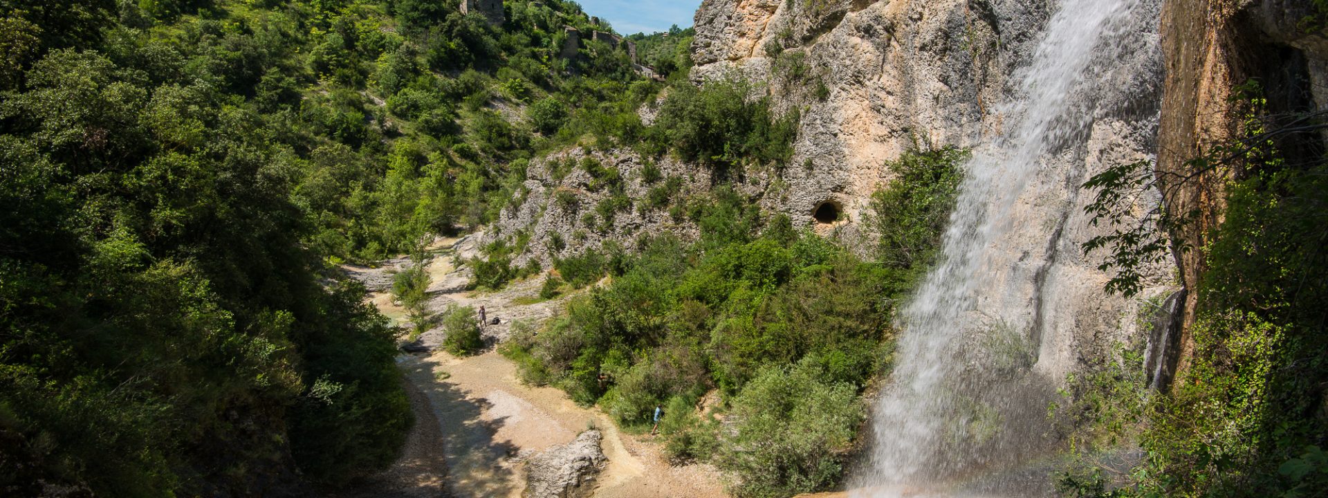 See the famous Rochecolombe waterfall flowing down the river